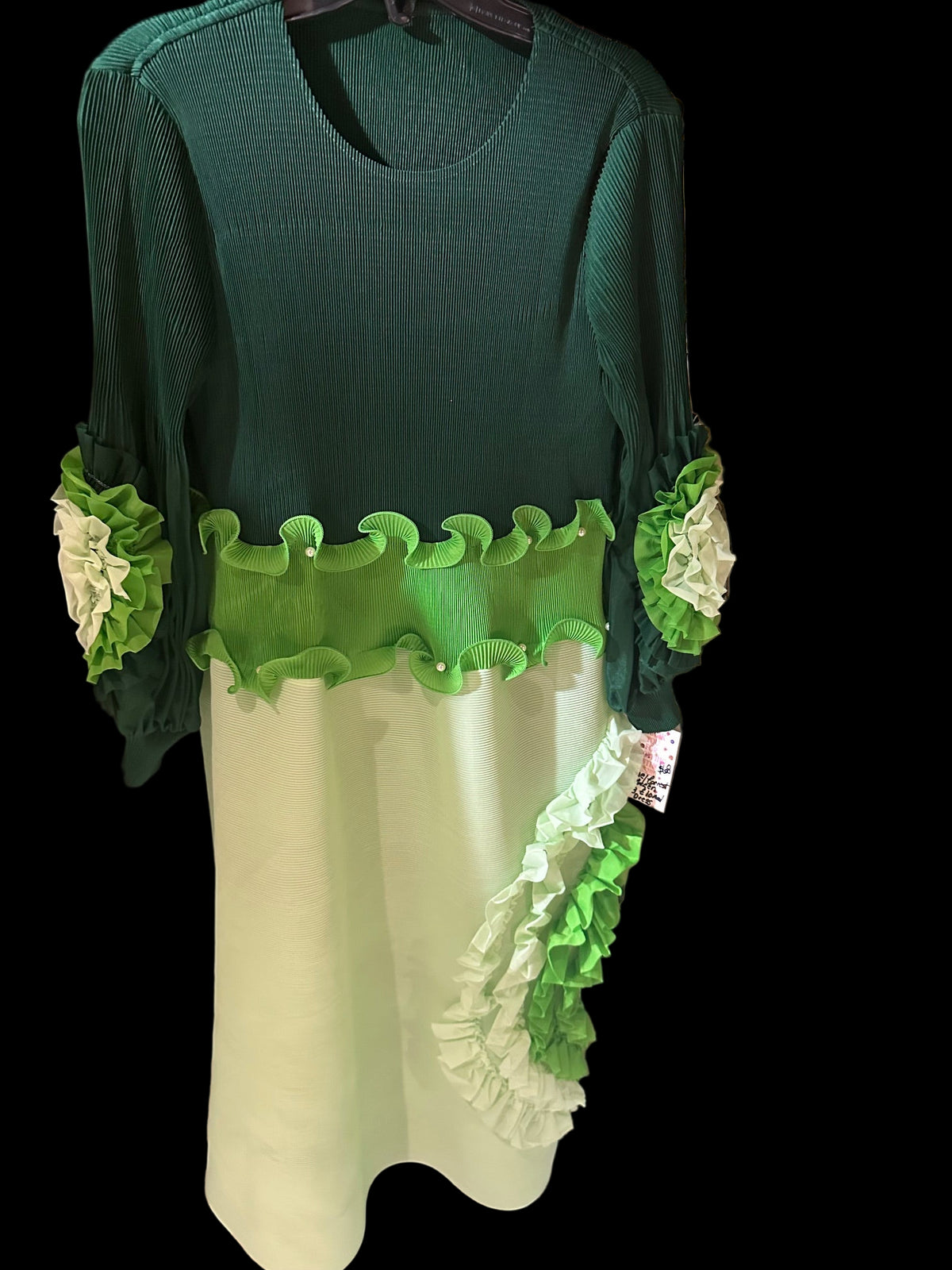 Green and white dress with ruffled details on a table with decorative items.