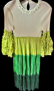 Green and white dress with ruffled sleeves and bottom on a hanger.